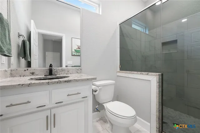 a bathroom with a granite countertop toilet sink and mirror