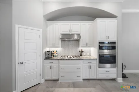 a kitchen with white cabinets and appliances