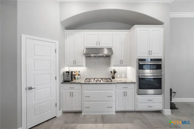 a kitchen with white cabinets and appliances
