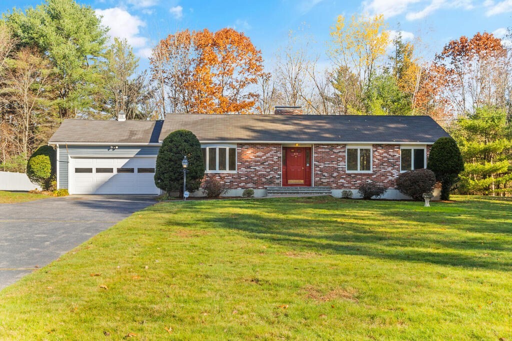 a front view of a house with a big yard and large trees