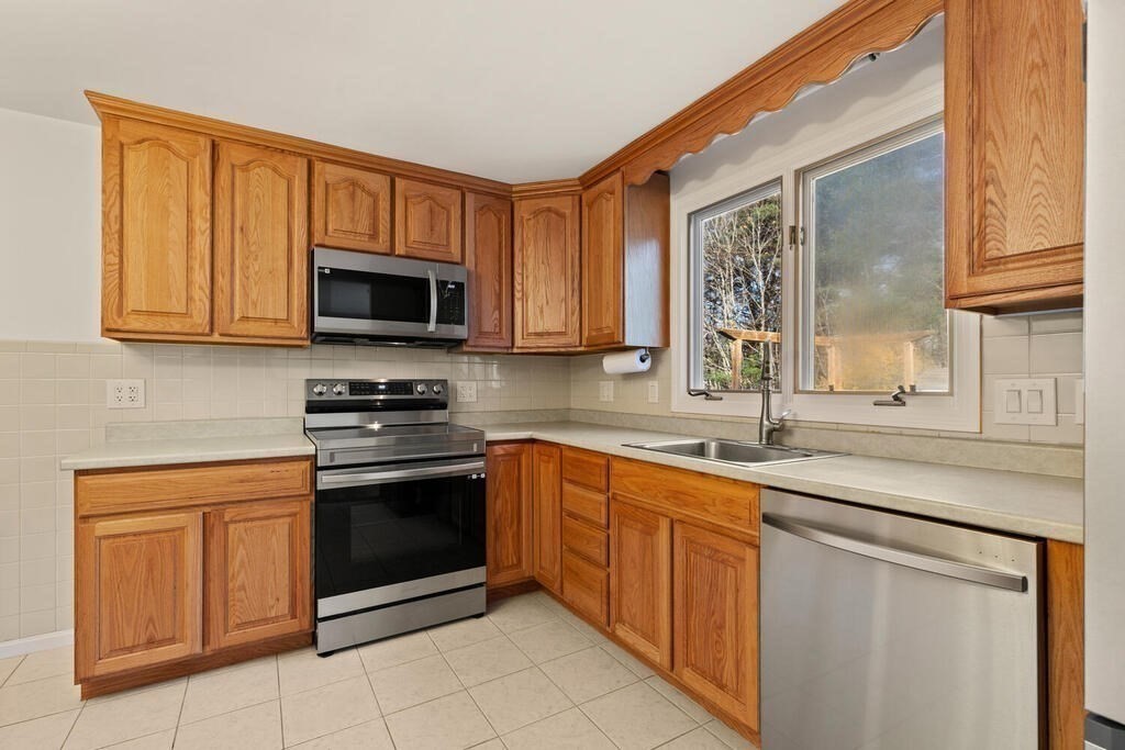 815 Great Road Stow, MA 01775 - Photo 13 of 32 a kitchen with stainless steel appliances granite countertop a stove microwave and sink
