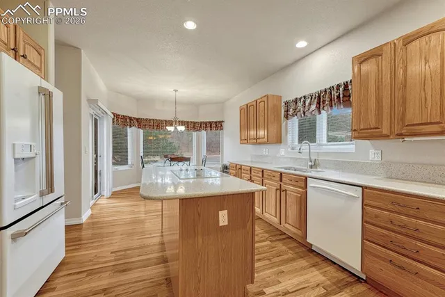 a open kitchen with stainless steel appliances granite countertop a refrigerator a sink dishwasher and white cabinets with wooden floor