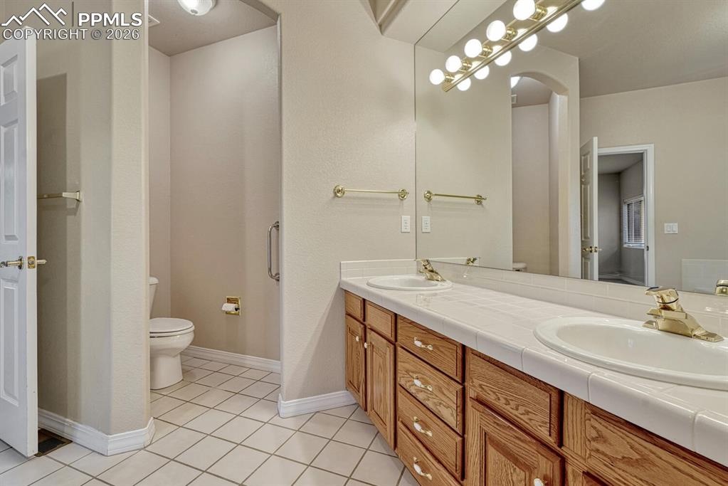 1665 Doe Run Point Colorado Springs, CO 80919 - Photo 21 of 49 a bathroom with a double vanity sink a toilet and a mirror