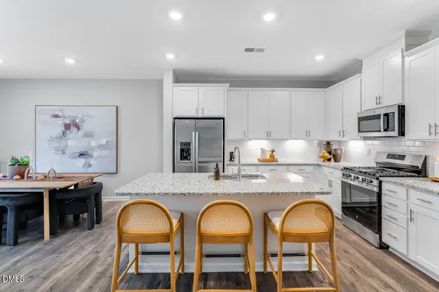 a kitchen with granite countertop kitchen island stainless steel appliances a refrigerator a stove a sink a dining table and chairs