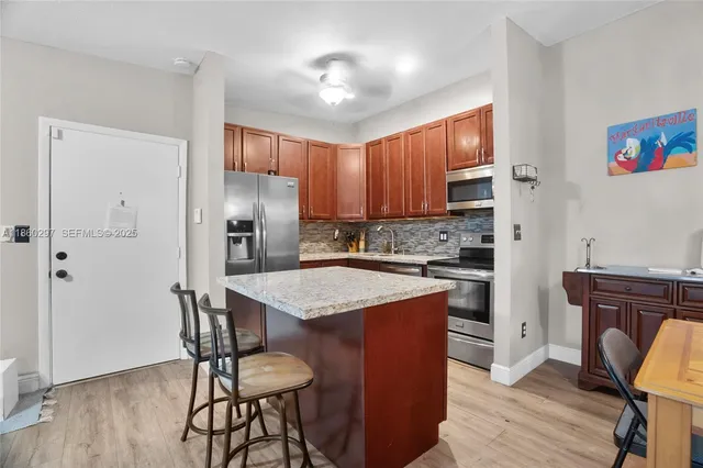 a kitchen with stainless steel appliances granite countertop a refrigerator a stove and a sink