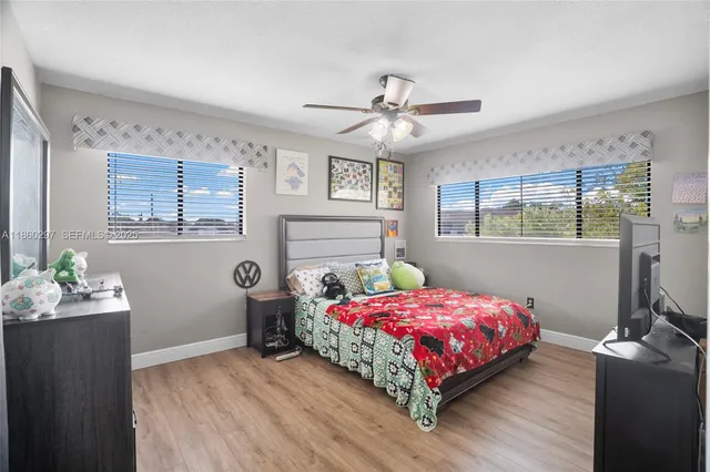 a bedroom with bed a flat tv screen and a dresser