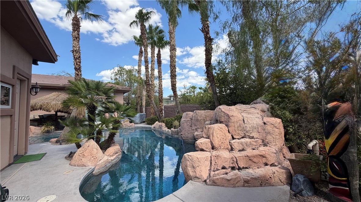 490 Toucan Ridge Court Henderson, NV 89012 - Photo 6 of 7 Towering palm trees and natural rock formations surround a tranquil private swimming pool.