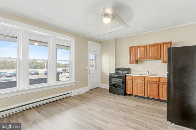 a kitchen with stainless steel appliances granite countertop a stove a sink dishwasher a refrigerator and white cabinets with wooden floor