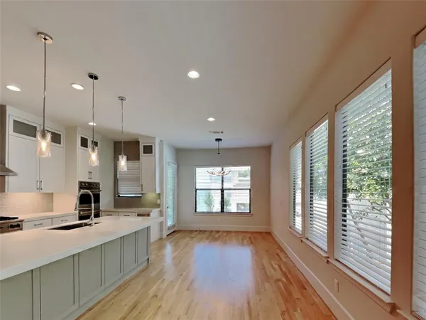 a large kitchen with kitchen island a large window a sink and stainless steel appliances