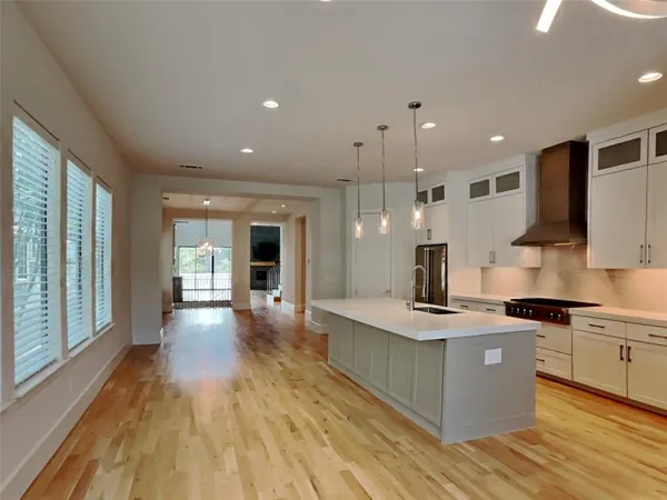 a kitchen with kitchen island a counter top space a sink a stove and a large window