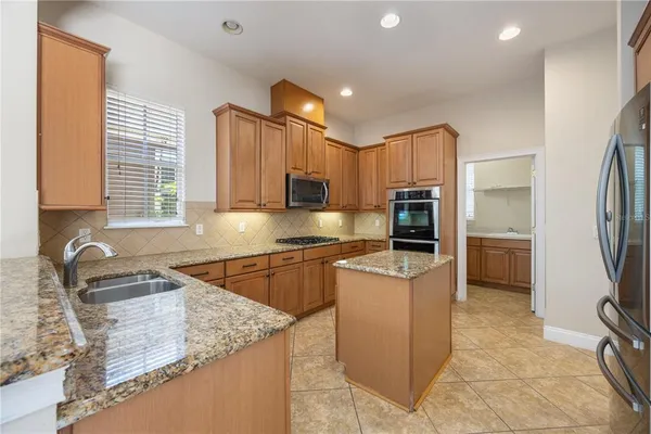 a kitchen with kitchen island granite countertop a sink stove and refrigerator
