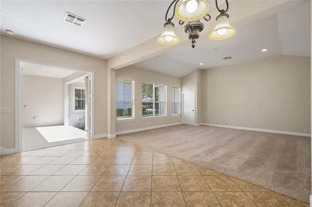 a view of an empty room with a chandelier fan