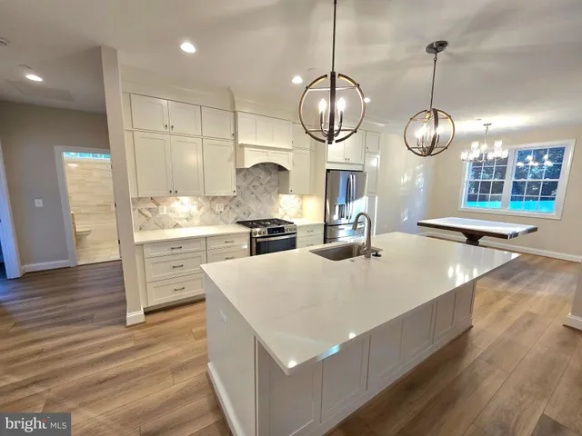 a large kitchen with kitchen island a stove a sink a center island and wooden floor