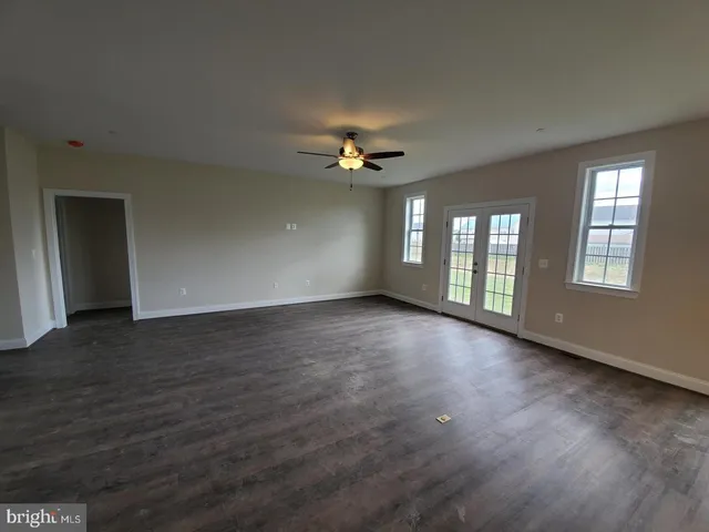 a view of an empty room with chandelier fan and wooden floor