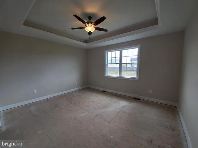 an empty room with a chandelier fan and windows
