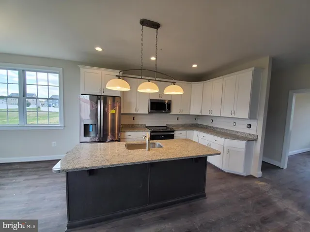 a kitchen with kitchen island granite countertop a sink window and stainless steel appliances
