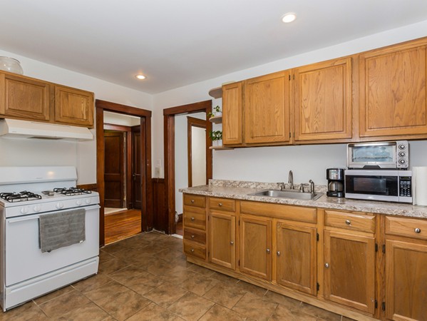 348 Lagrange Street Boston, MA 02132 - Photo 8 of 25 a kitchen with stainless steel appliances granite countertop a stove a sink and a refrigerator with wooden cabinets