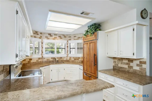 a large kitchen with granite countertop a sink and a stove top oven
