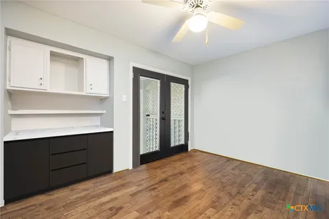 a view of empty room with wooden floor and fan