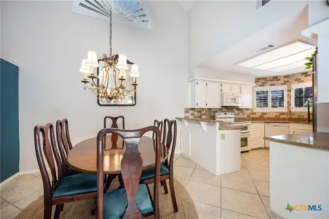 a dining room filled chandelier and kitchen view
