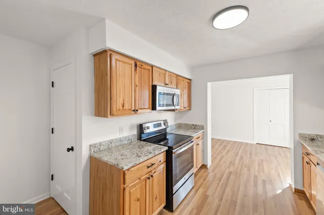 a kitchen with stainless steel appliances granite countertop a stove and a wooden floors