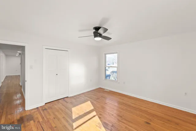 a view of a bedroom with wooden floor and a ceiling fan