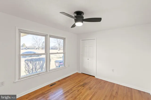 a view of an empty room with wooden floor and a window