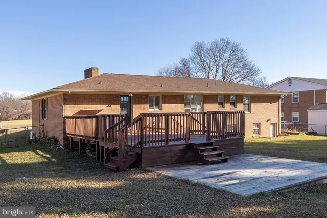a view of a house with a wooden deck and furniture