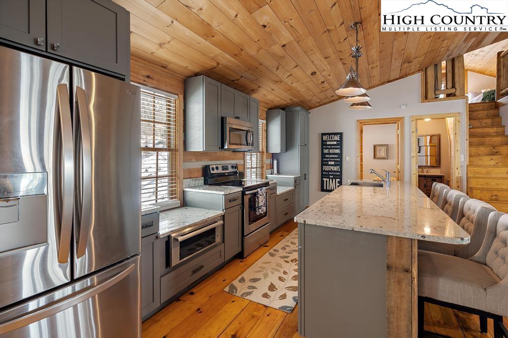 3855 Howard's Creek Road Boone, NC 28607 - Photo 12 of 38 a kitchen with stainless steel appliances granite countertop a refrigerator a stove and a sink with wooden floors