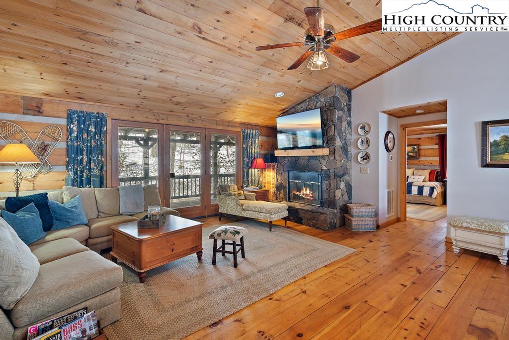 3855 Howard's Creek Road Boone, NC 28607 - Photo 17 of 38 a living room with furniture a fireplace and a chandelier