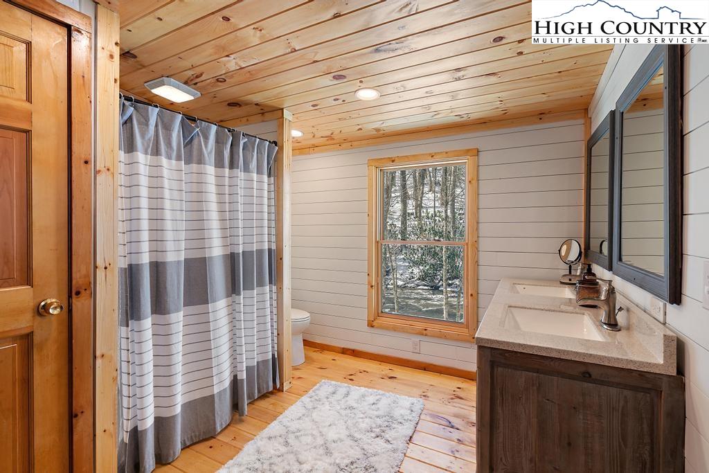 3855 Howard's Creek Road Boone, NC 28607 - Photo 23 of 38 a bathroom with a sink a mirror and next to a window