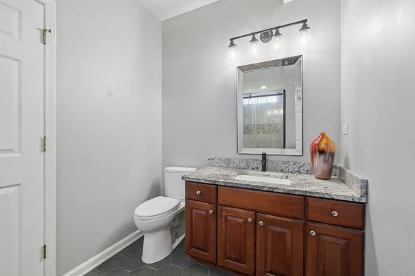 a bathroom with a granite countertop sink toilet and mirror