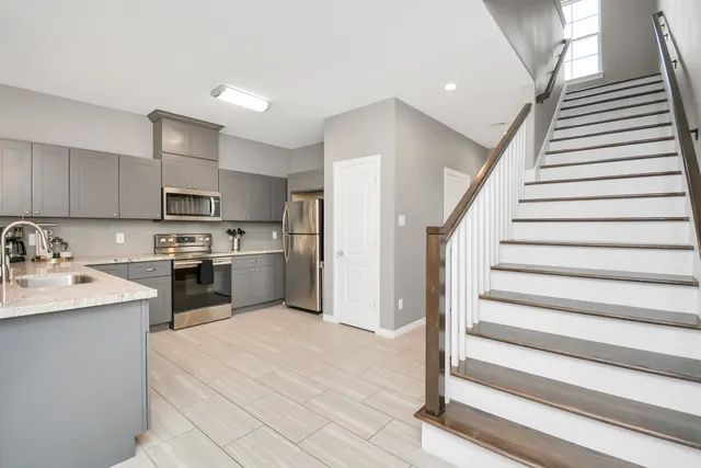 a kitchen with granite countertop a sink stainless steel appliances and white cabinets