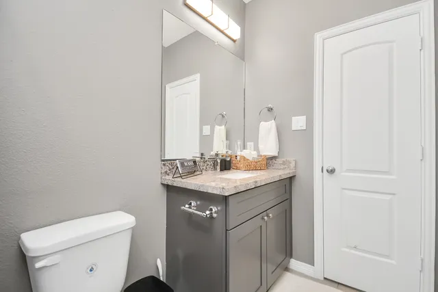 a bathroom with a granite countertop sink a toilet and a mirror