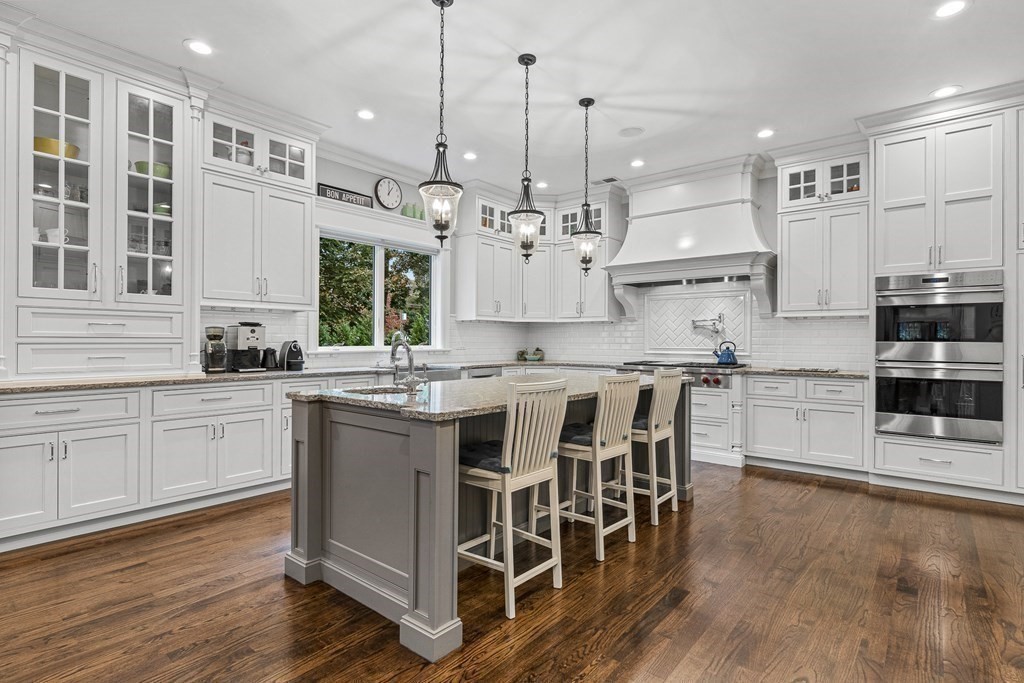 3 Ravine Road Winchester, MA 01890 - Photo 14 of 42 a open kitchen with stainless steel appliances granite countertop a stove top oven a sink dishwasher and a dining table with wooden floor