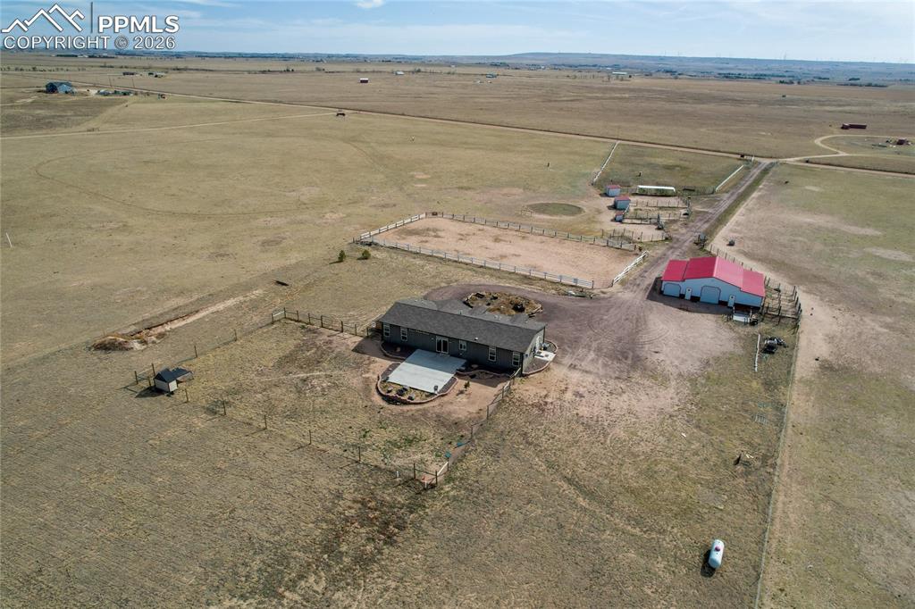 7880 J D Johnson Road Peyton, CO 80831 - Photo 31 of 50 Expansive rural property featuring a single-story residence, a large red-roofed barn, and multiple fenced areas