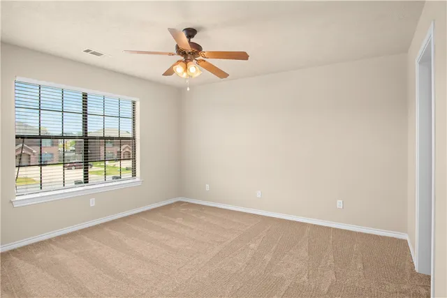 an empty room with windows and fan
