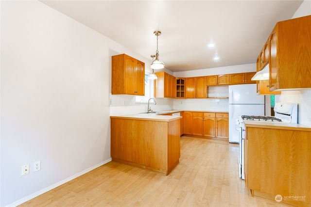 a kitchen with stainless steel appliances granite countertop a sink and a wooden floor