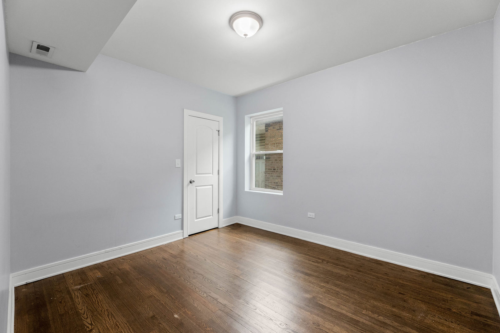 7752 South Wood Street, Unit 1 Chicago, IL 60620 - Photo 5 of 12 an empty room with wooden floor and windows