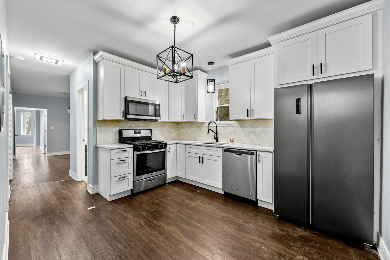 7752 South Wood Street, Unit 1 Chicago, IL 60620 - Photo 7 of 12 a kitchen with stainless steel appliances granite countertop a refrigerator a stove a microwave oven a sink with wooden floor and cabinets
