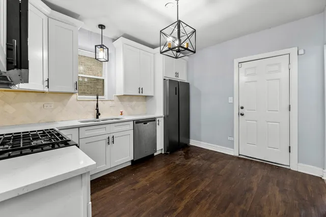 a kitchen with stainless steel appliances a refrigerator a sink dishwasher a stove and white cabinets with wooden floor