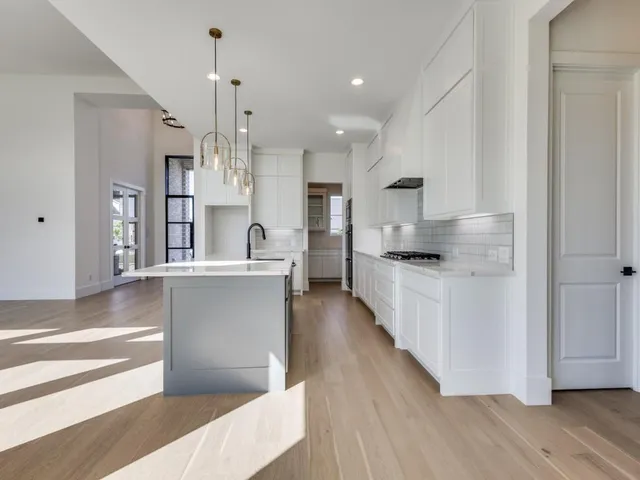 a large kitchen with cabinets wooden floor and stainless steel appliances