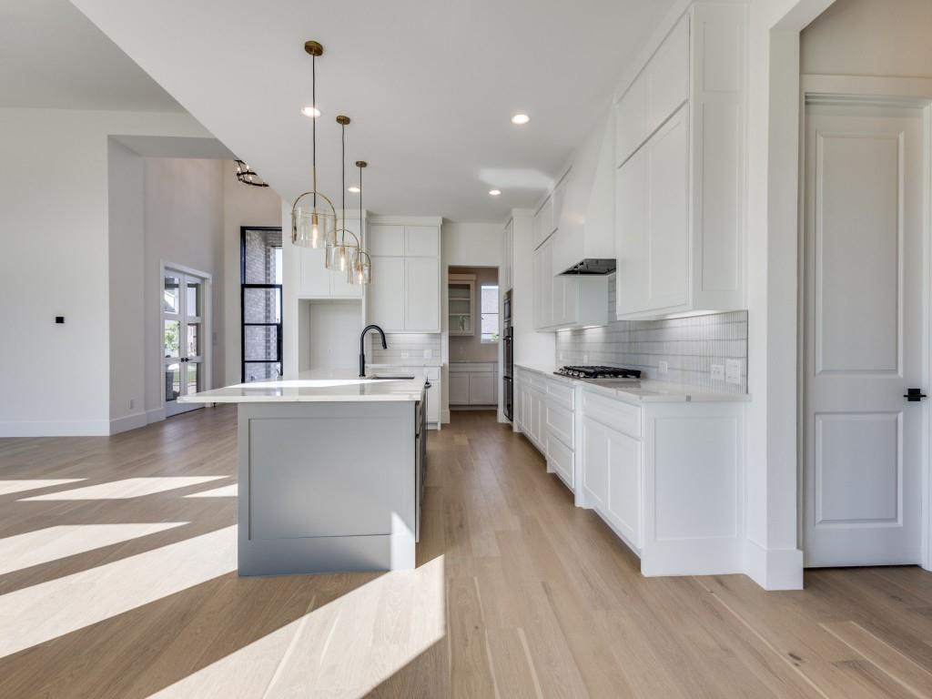 1045 Bent Tree Lane Gunter, TX 75058 - Photo 4 of 25 a large kitchen with cabinets wooden floor and stainless steel appliances