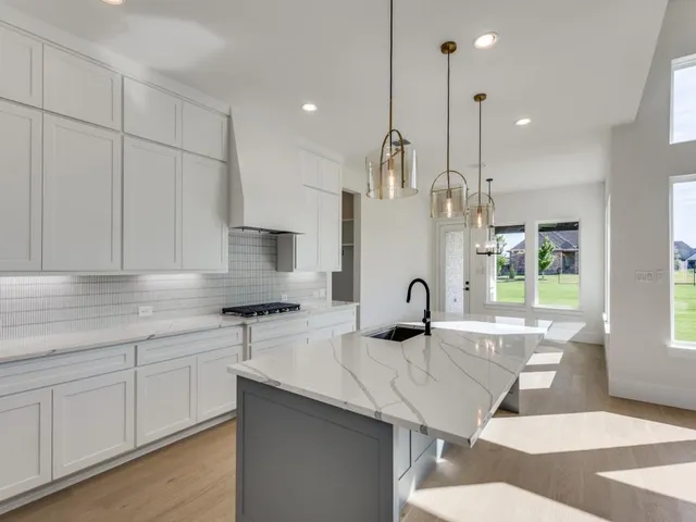 a kitchen with stainless steel appliances granite countertop a sink a stove and a wooden floors