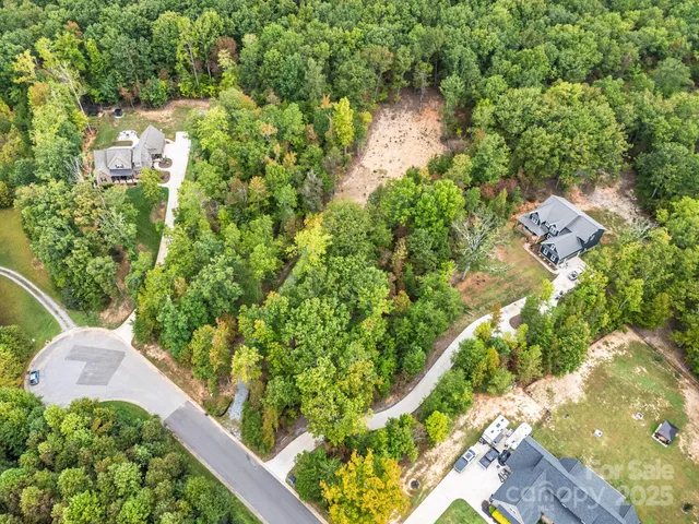 an aerial view of residential house with outdoor space and trees all around