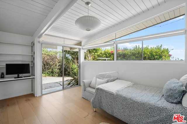 a bedroom with a bed and large windows
