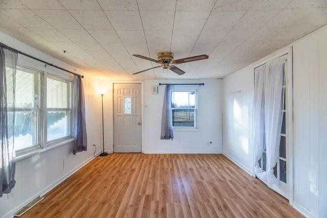a view of empty room with wooden floor and fan