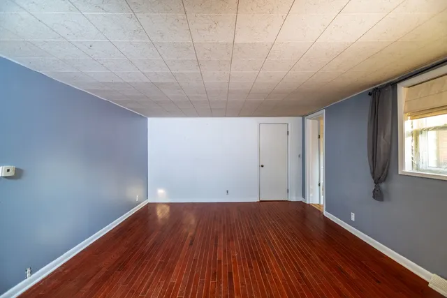 a view of a big room with wooden floor and windows