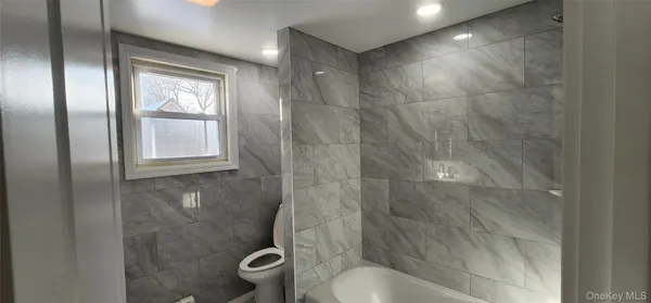 a bathroom with a granite countertop bathtub shower and toilet