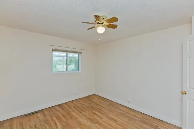 an empty room with a window and wooden floor